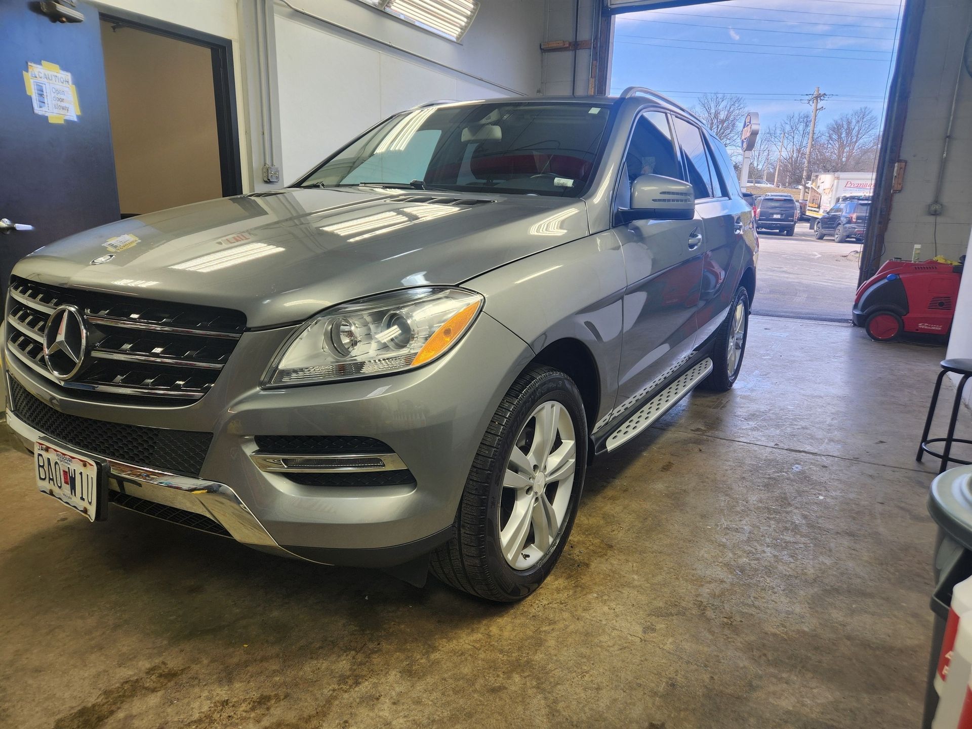 Silver Mercedes SUV parked inside a garage with its front end facing the camera.