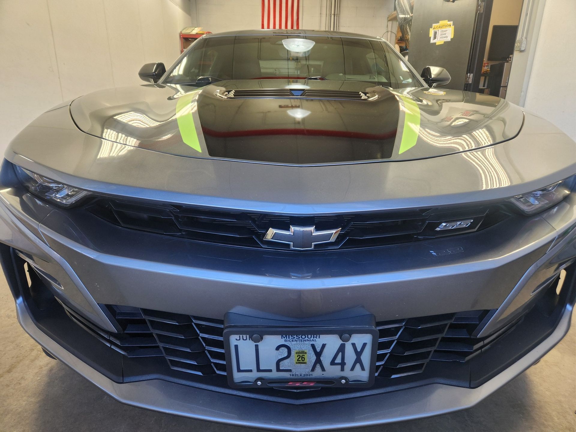 Black Chevrolet sports car with a hood scoop, front view in a garage, license plate visible