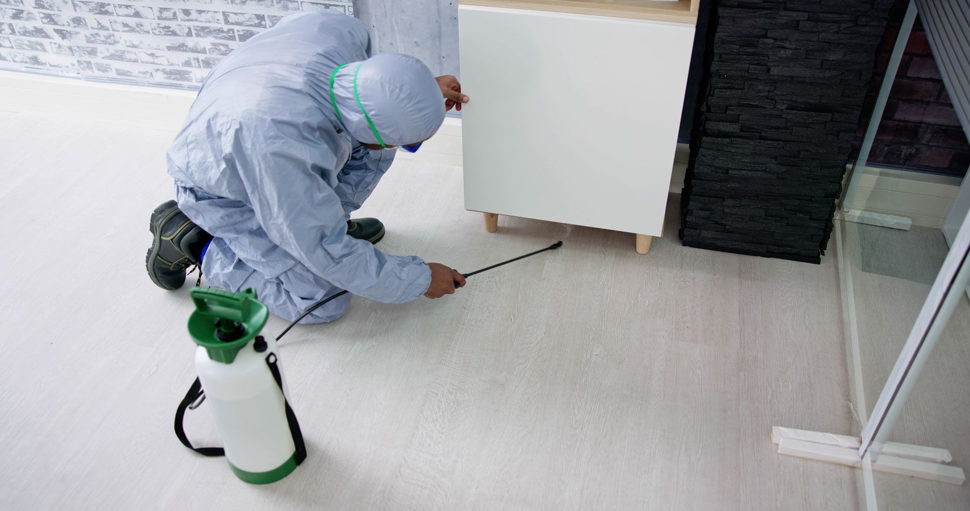 spraying disinfectant on a floor near a cabinet and window
