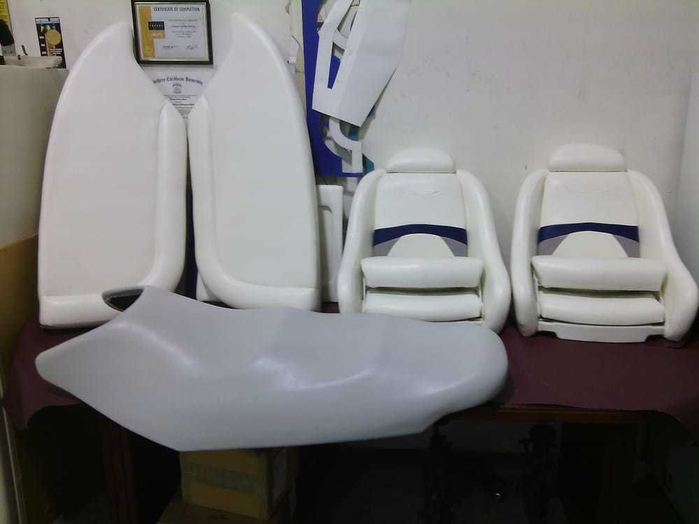 Upholstered white boat seats and panels arranged on a table in a workshop.