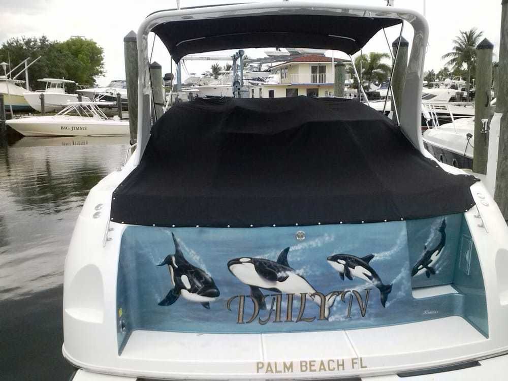 A white yacht docked in a marina with a decal of orca whales and the name 