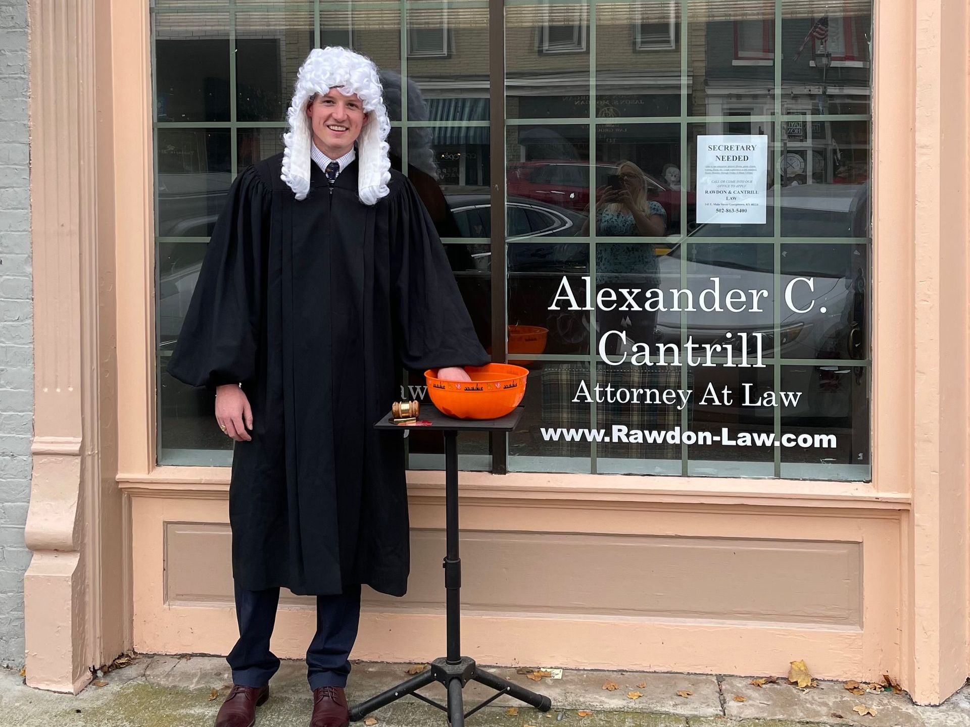 A man dressed as a judge is standing in front of a building.