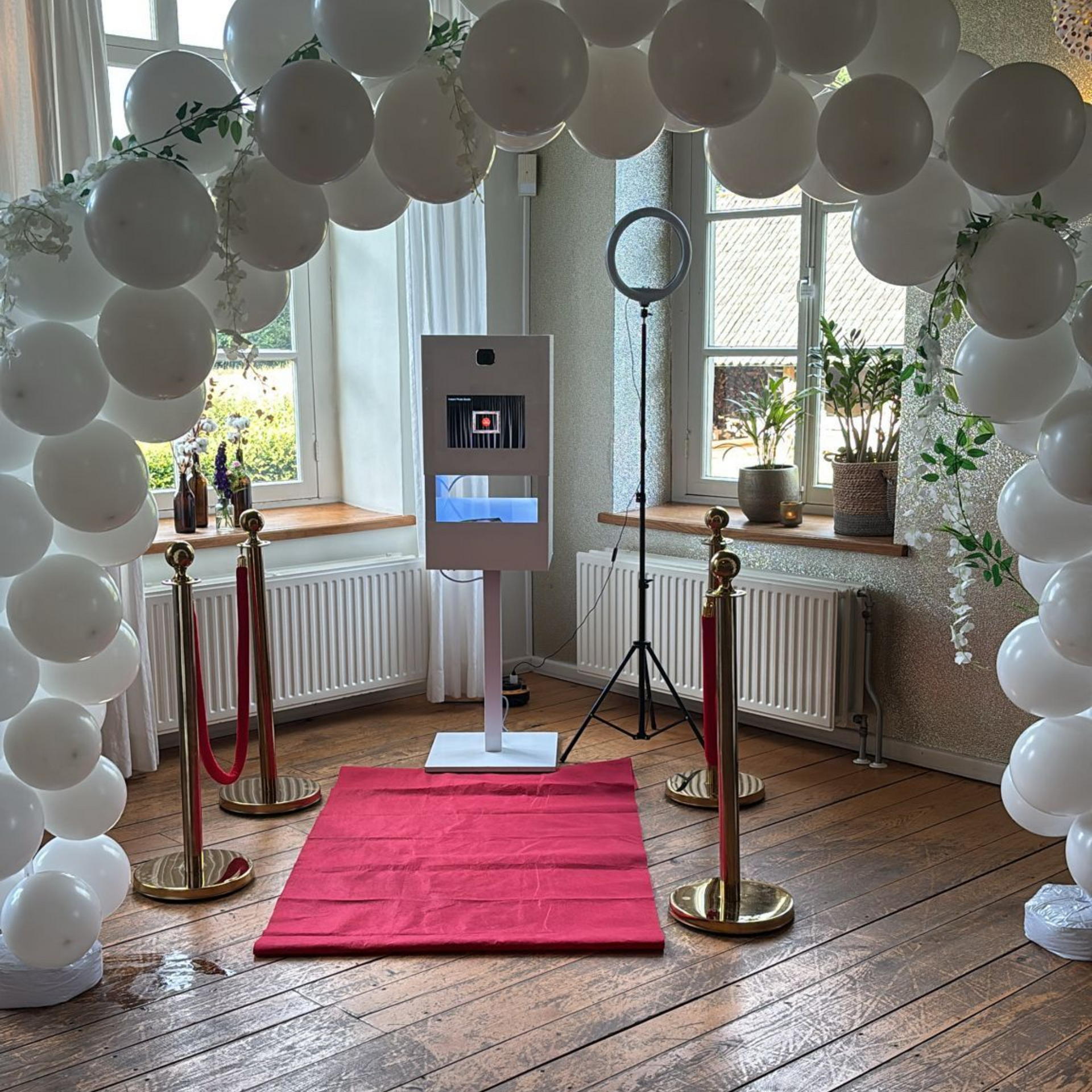 Een fotohokje is omringd door ballonnen en een rode loper.
