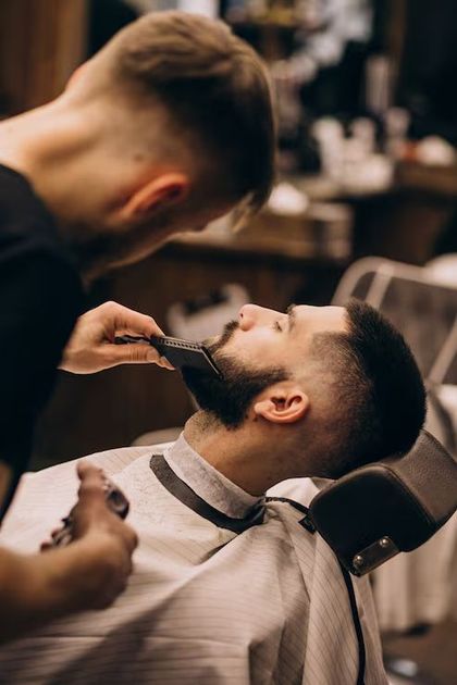 Barbero afeitando la barba de un cliente con una navaja de afeitar en una barbería.