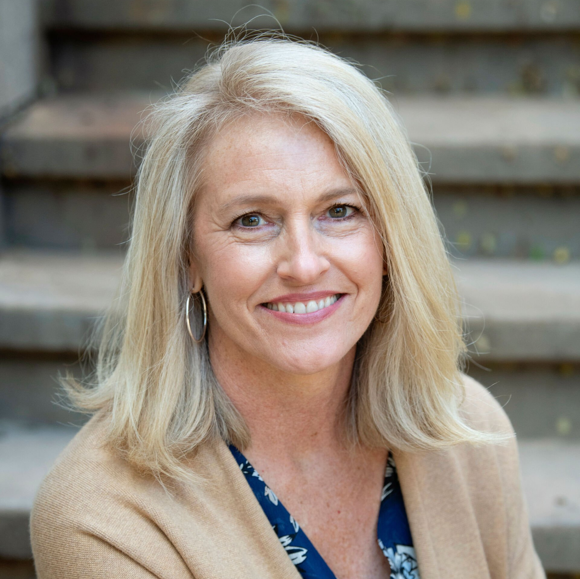 A woman is smiling for the camera while sitting on a set of stairs.
