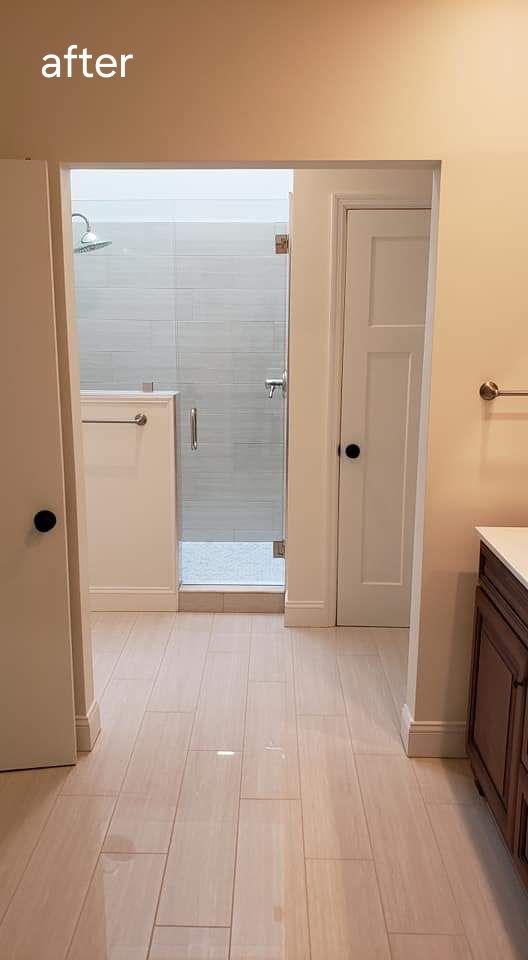 Bathroom with open doorway to a tiled shower, light wood floor, and white walls.