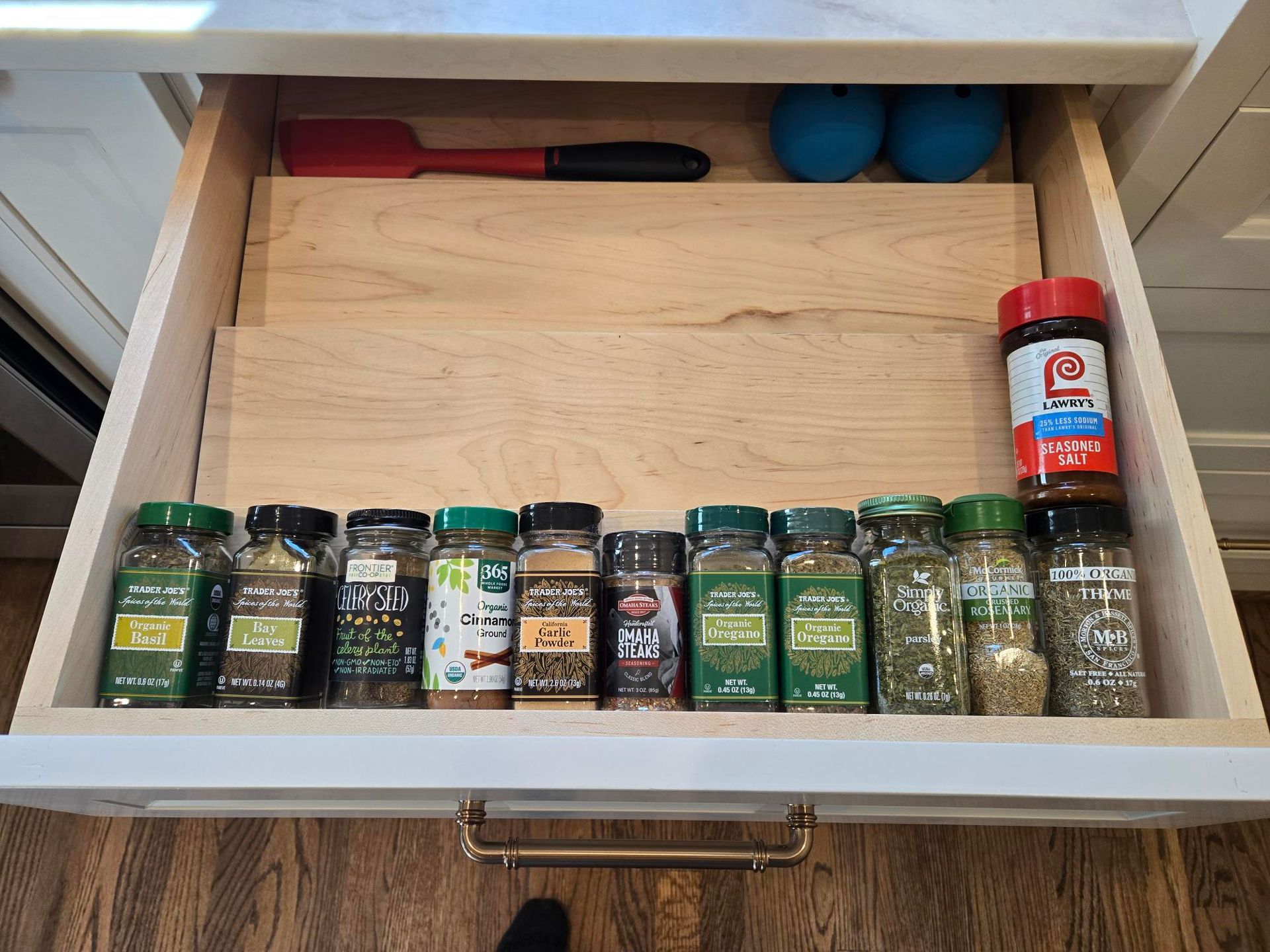 Kitchen drawer with assorted spice jars lined up and a knife at the back