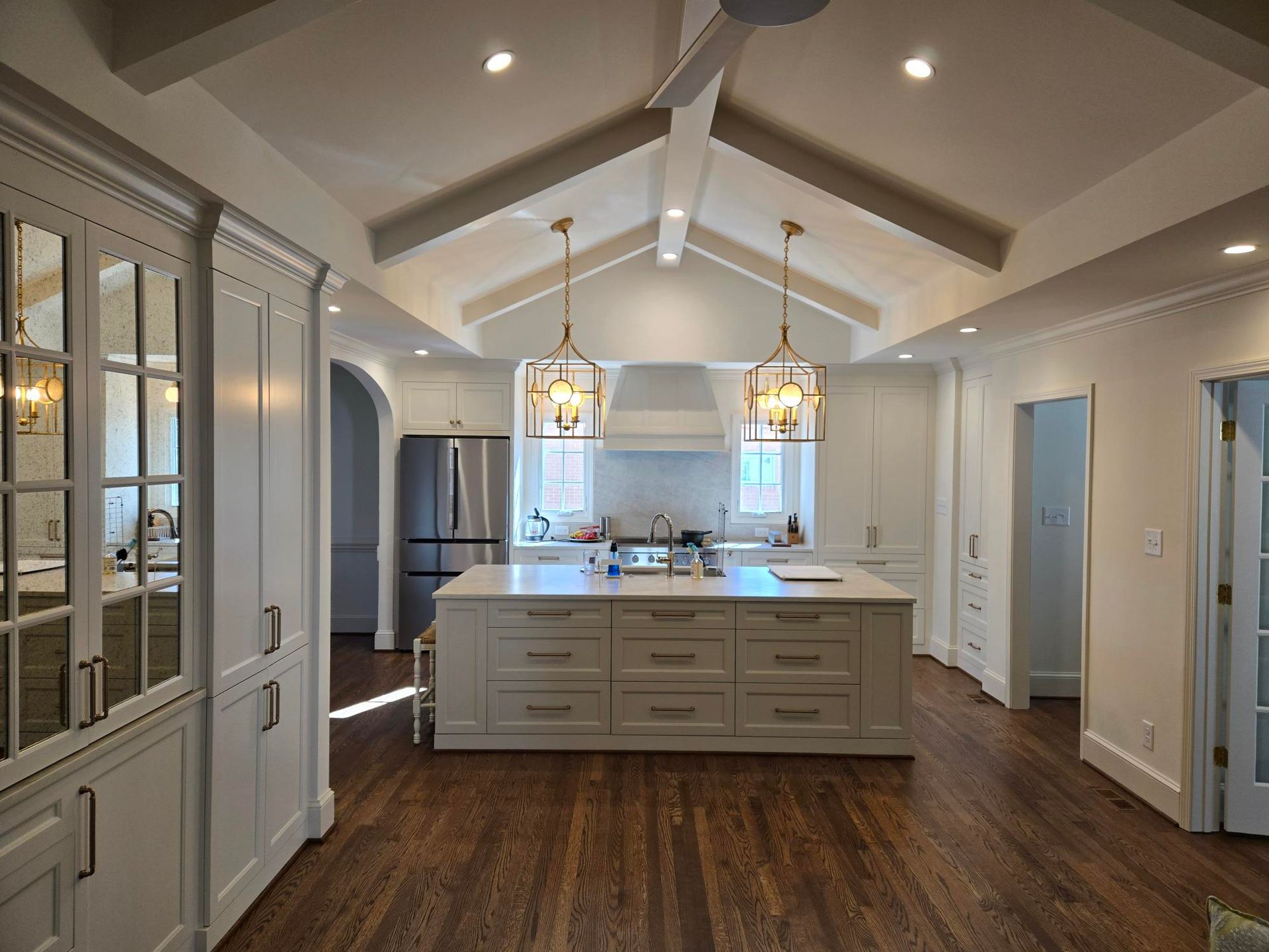 Bright modern kitchen with white cabinetry, central island, pendant lights, and wood floors
