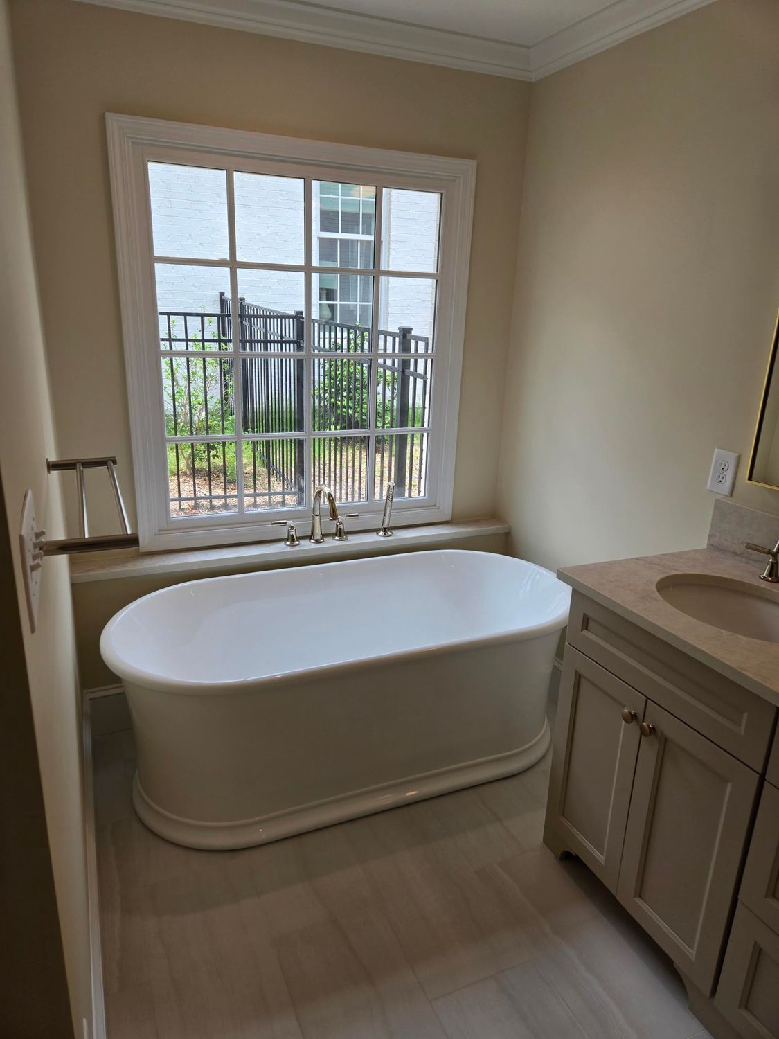 Modern bathroom with a freestanding tub by a window and a vanity sink on the right.