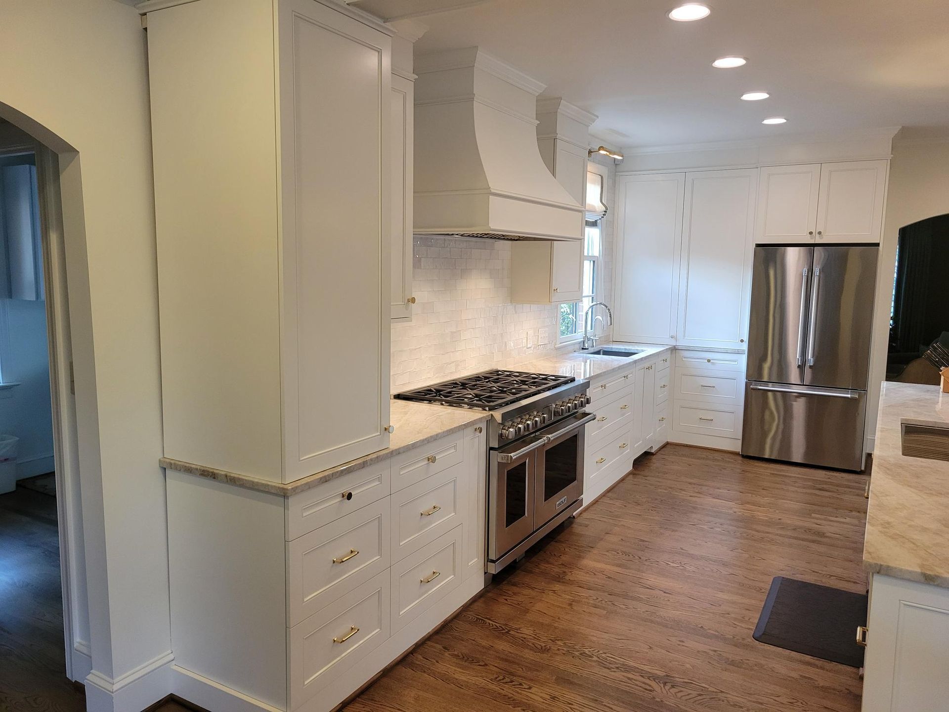 Bright modern kitchen with white cabinets, stainless steel appliances, and hardwood floors