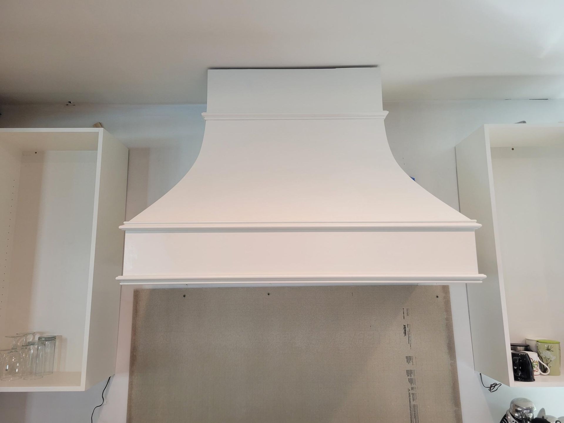 White kitchen range hood above an unfinished wall opening