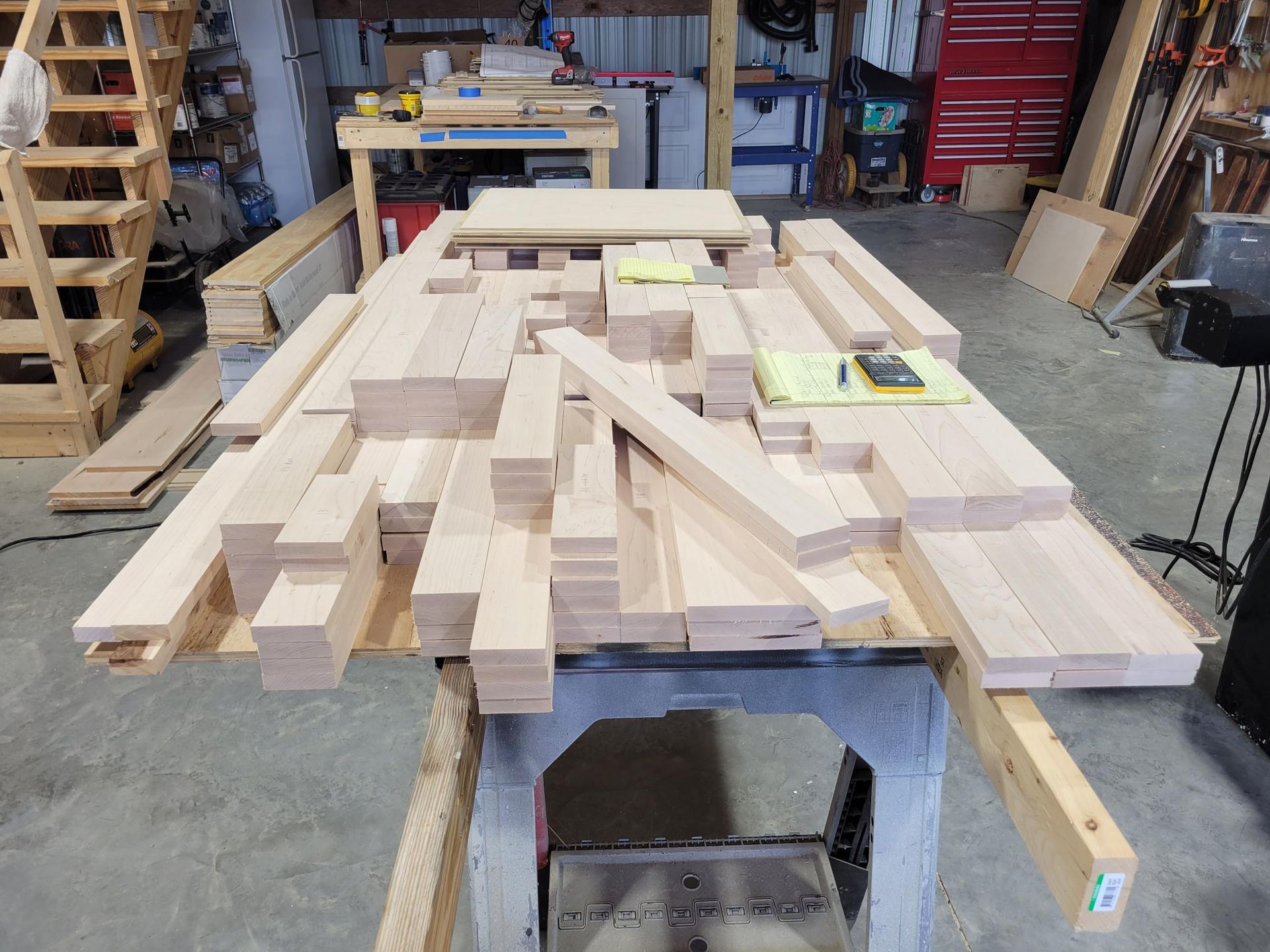 Stacked lumber and wood planks on a workbench in a workshop garage.