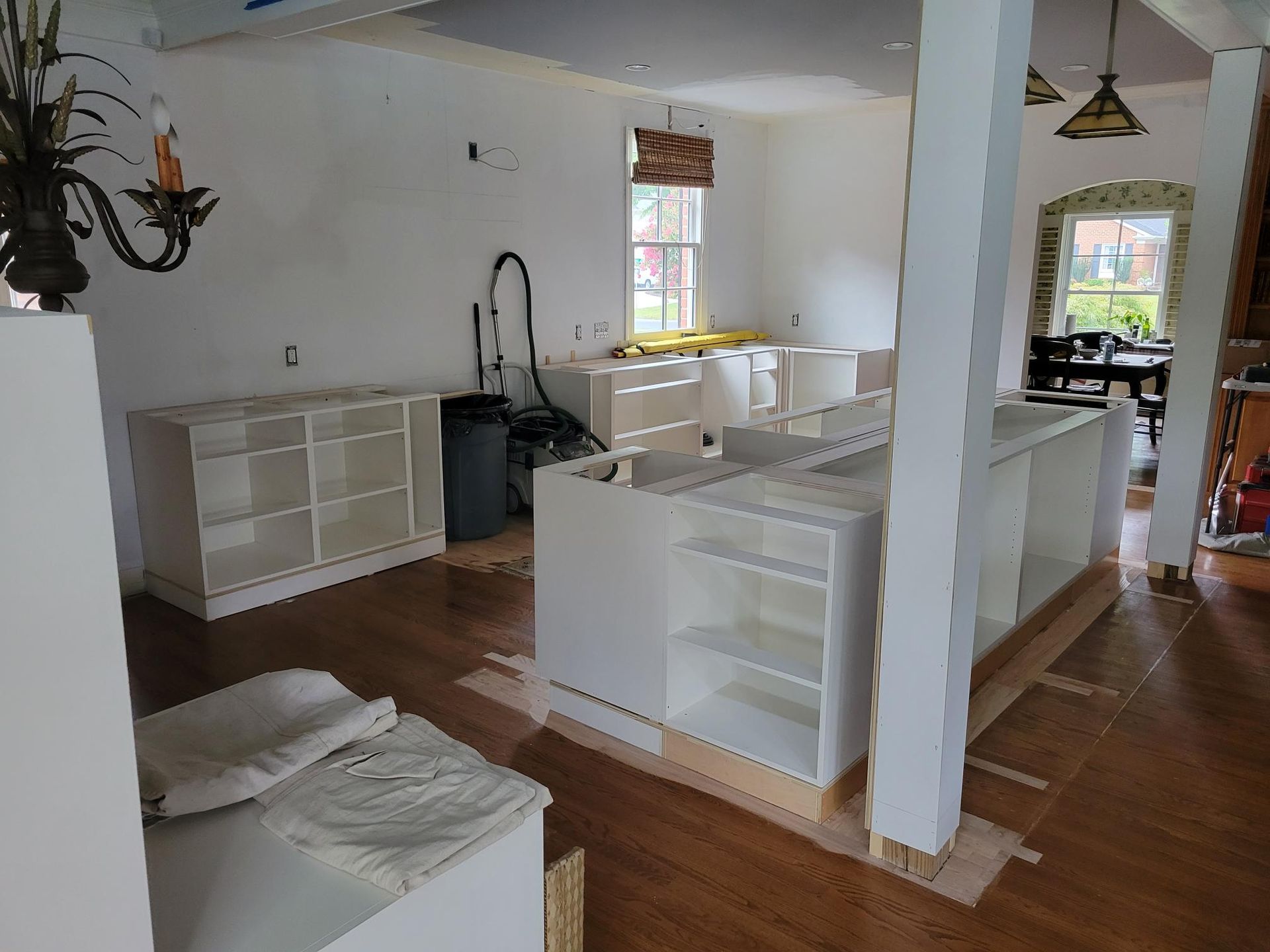 Bright white kitchen with island, cabinets, and dining area in a sunlit open-plan room