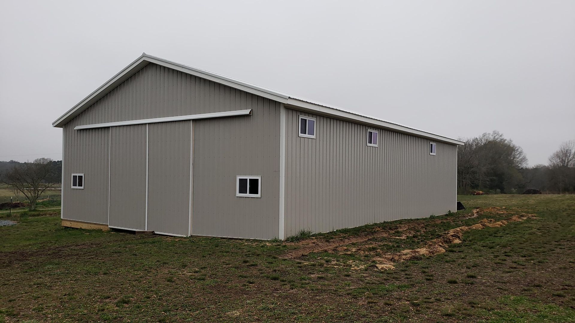 Gray metal barn on a grassy field under an overcast sky