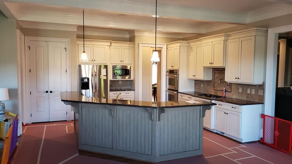 Spacious kitchen with cream cabinets, stainless appliances, and a large blue island under pendant lights.