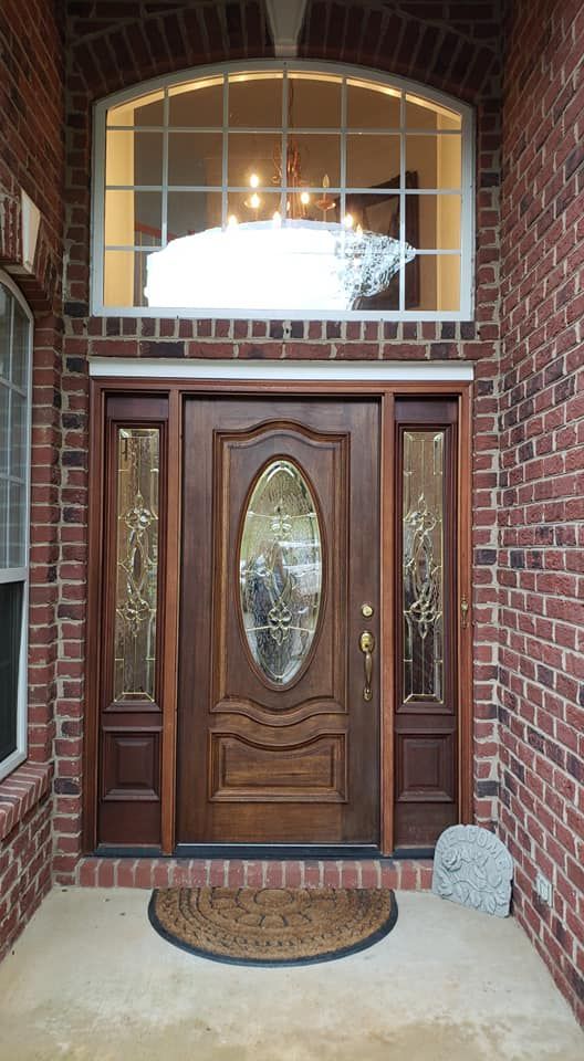 Brick house front door with oval glass panel, sidelights, and arched transom window