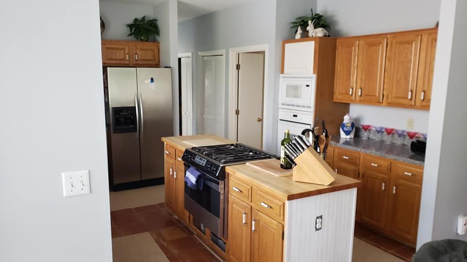 Bright kitchen with wooden cabinets, stainless fridge, gas stove, and a central island with cutting boards.