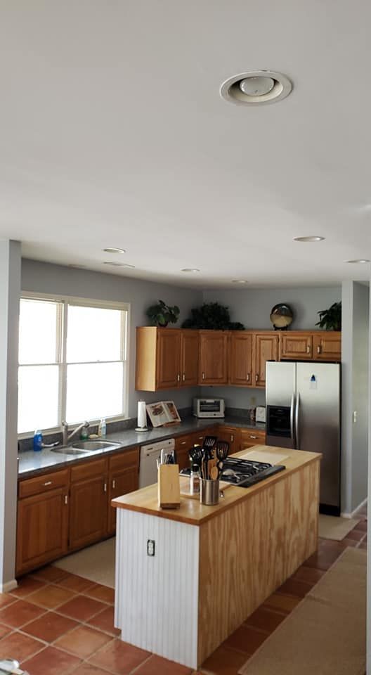 Bright kitchen with wood cabinets, stainless fridge, tile floor, and a central island under a white ceiling