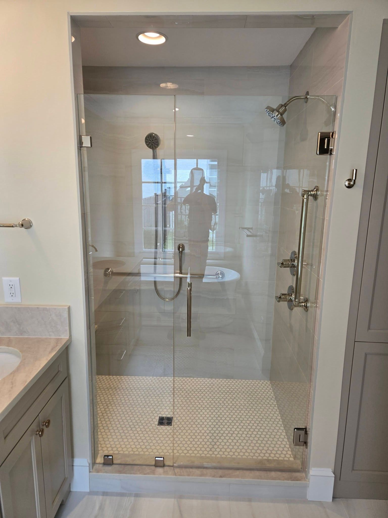 Glass walk-in shower with chrome fixtures and tiled floor in a modern bathroom