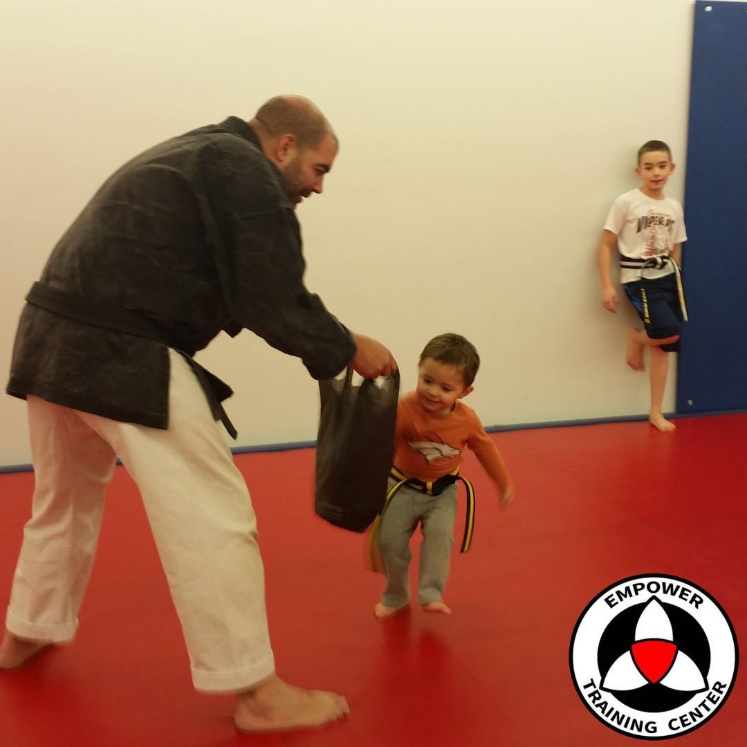 A group of children are practicing karate with a teacher in a gym.