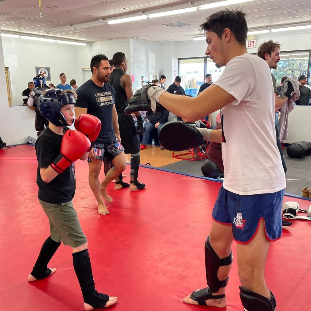 A group of children are practicing karate with a teacher in a gym.