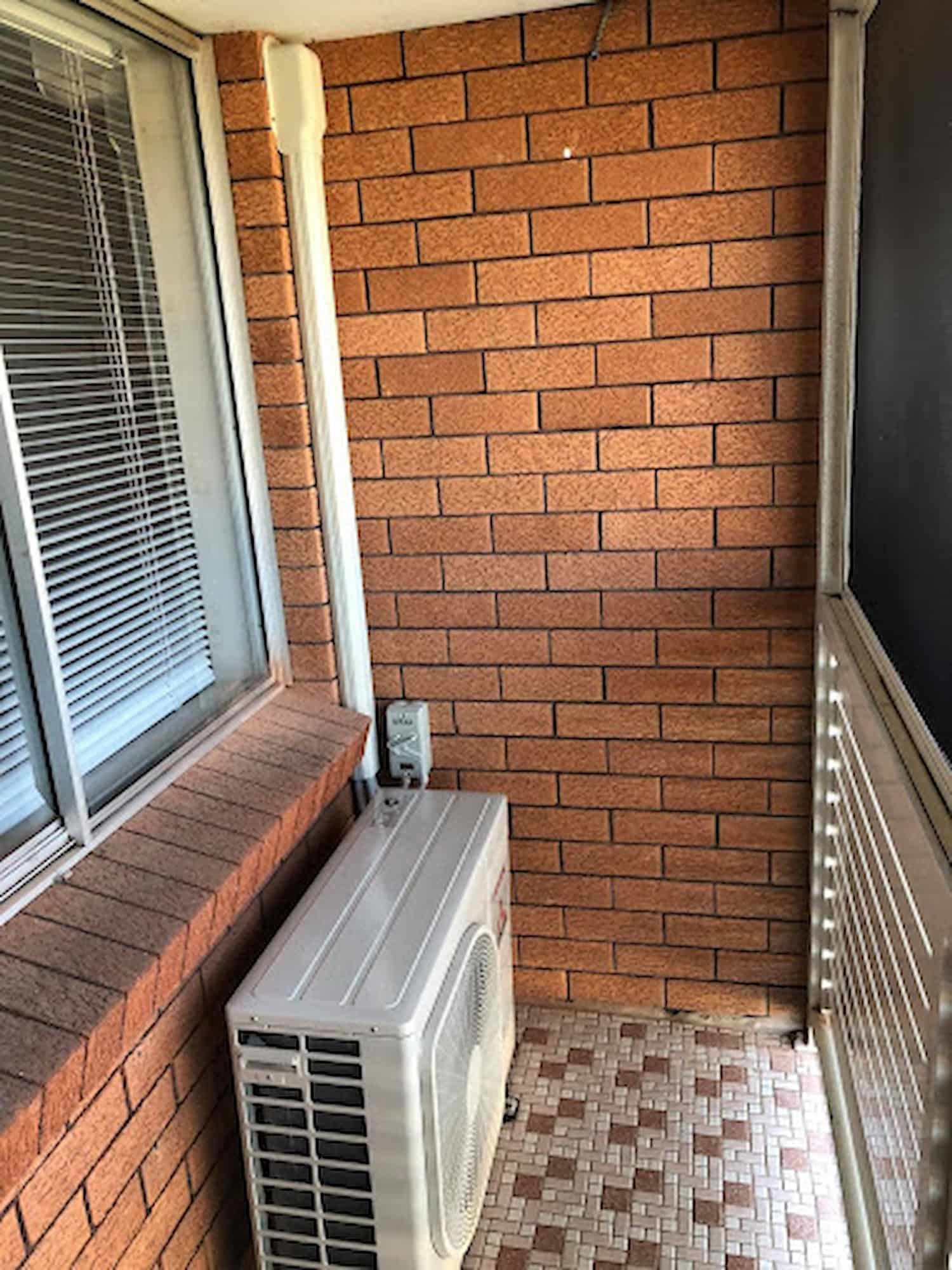 Balcony with An Air Conditioner Unit, Tiled Floor, and Window Blinds — Steve's Air Conditioning in Kanahooka, NSW