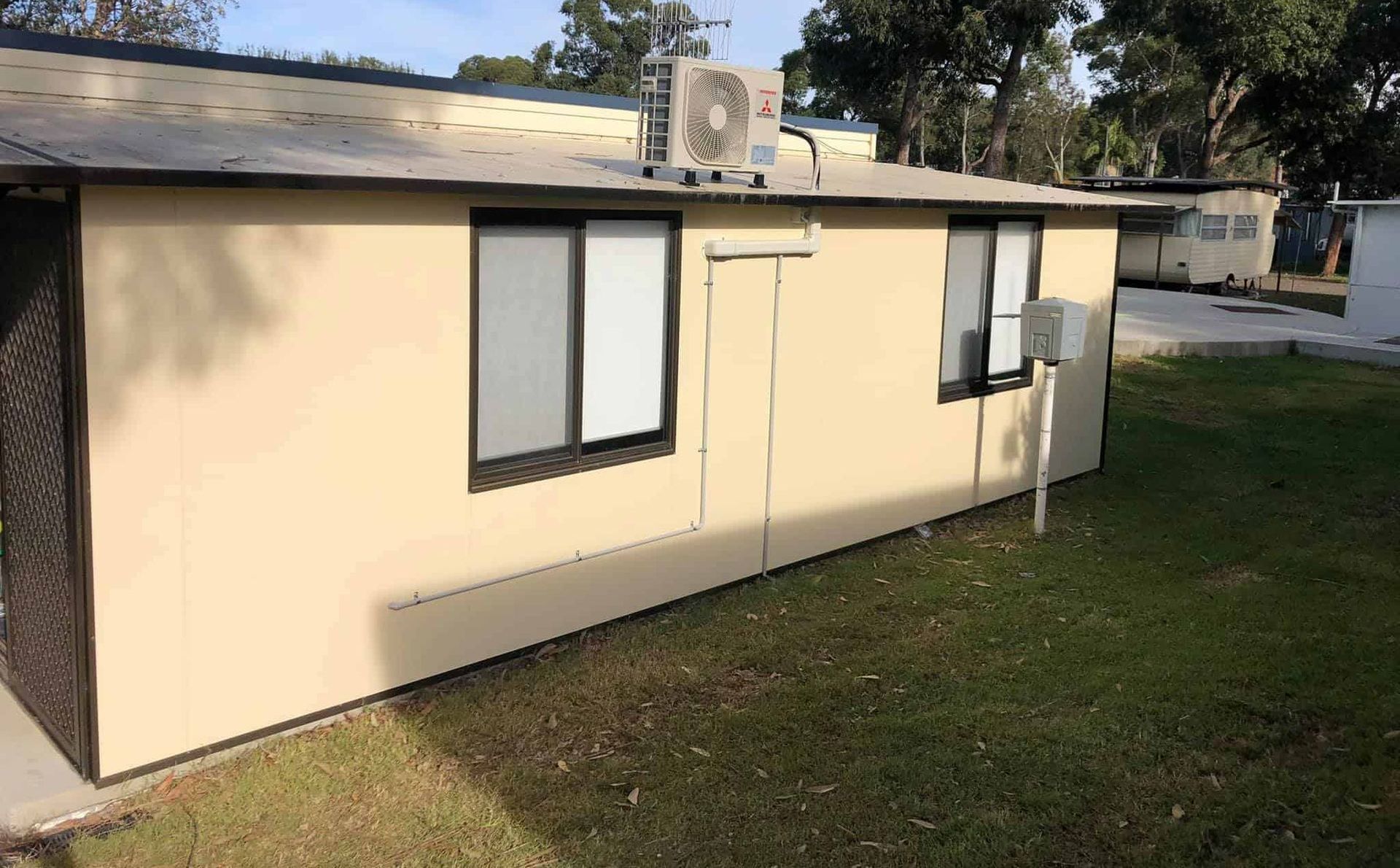 Small Beige Portable Building with Windows and An AC Unit — Steve's Air Conditioning in Kanahooka, NSW