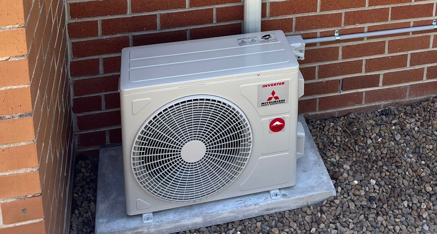 An Air Conditioner Unit Next To A  Brick Wall — Steve's Air Conditioning in Lakeside Dr, NSW