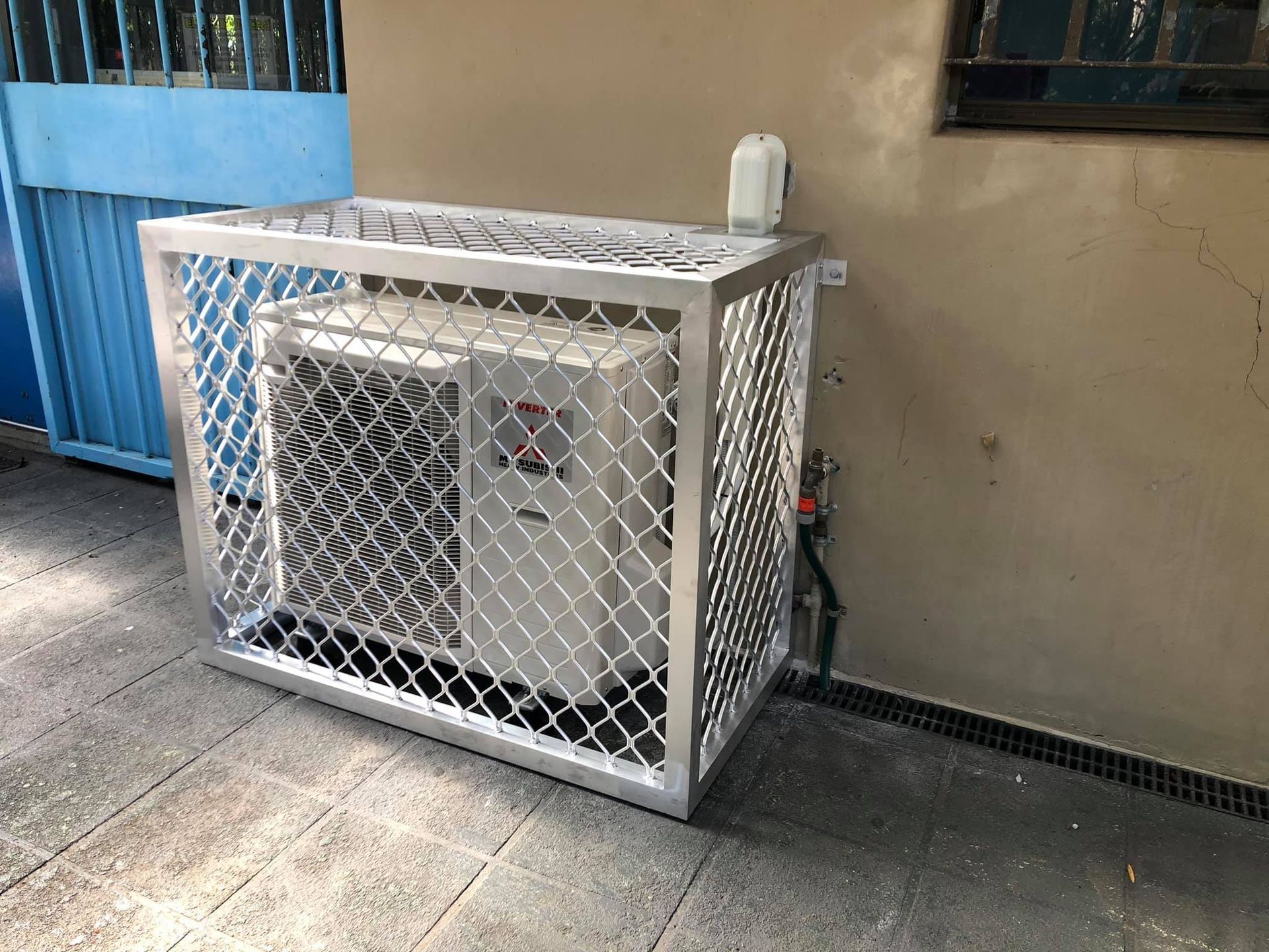 Air Conditioning Unit Enclosed in A White Metal Cage Beside a Building Wall — Steve's Air Conditioning in Kanahooka, NSW