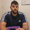Um homem com barba está sentado à mesa segurando um objeto roxo.