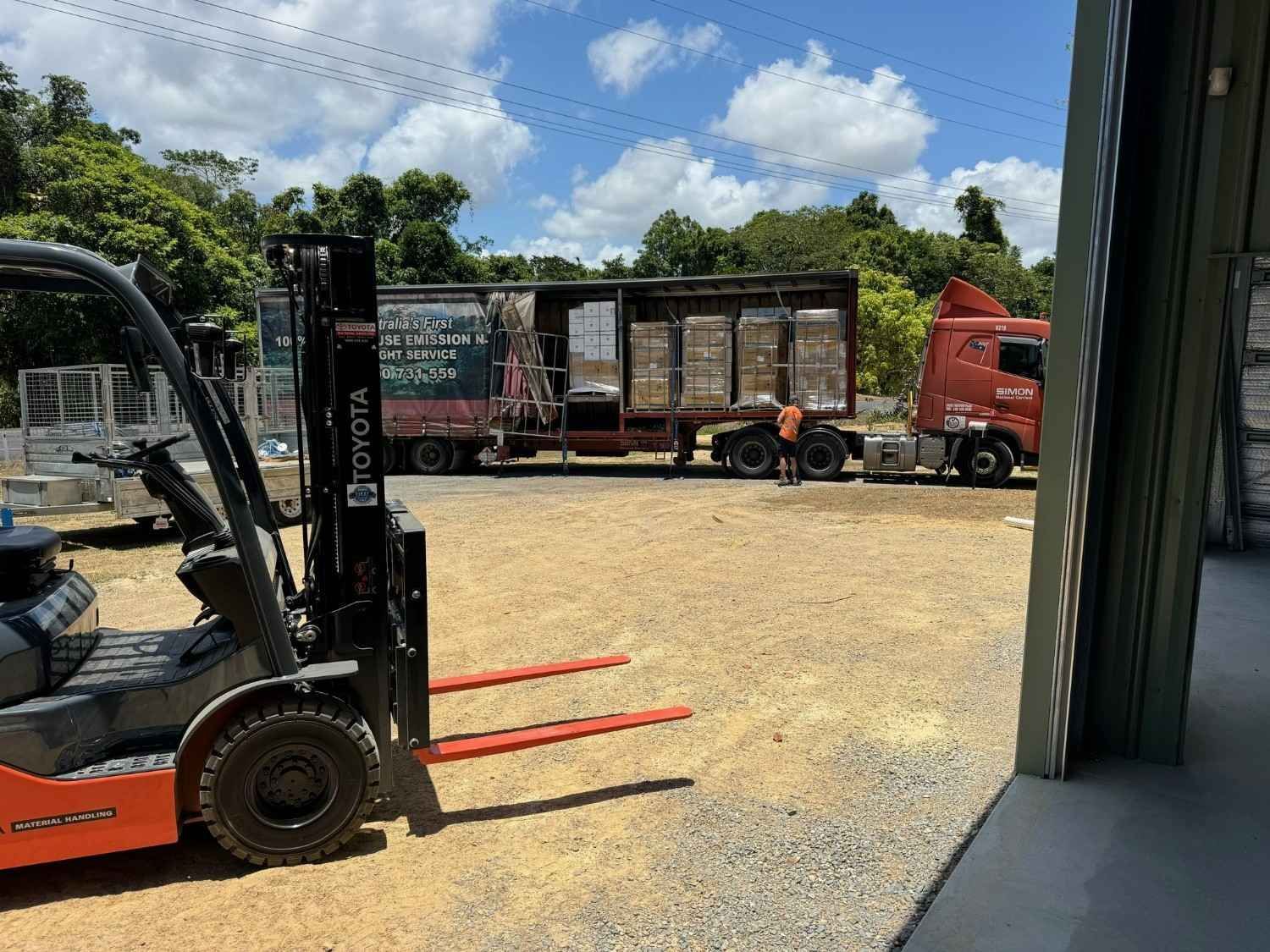 Forklift with red forks in a gravel yard beside a red semi-truck — Magneto HVAC in Portsmith, QLD