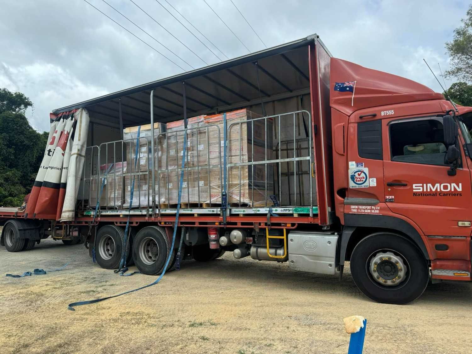 Red flatbed truck carrying stacked cargo — Magneto HVAC in Portsmith, QLD
