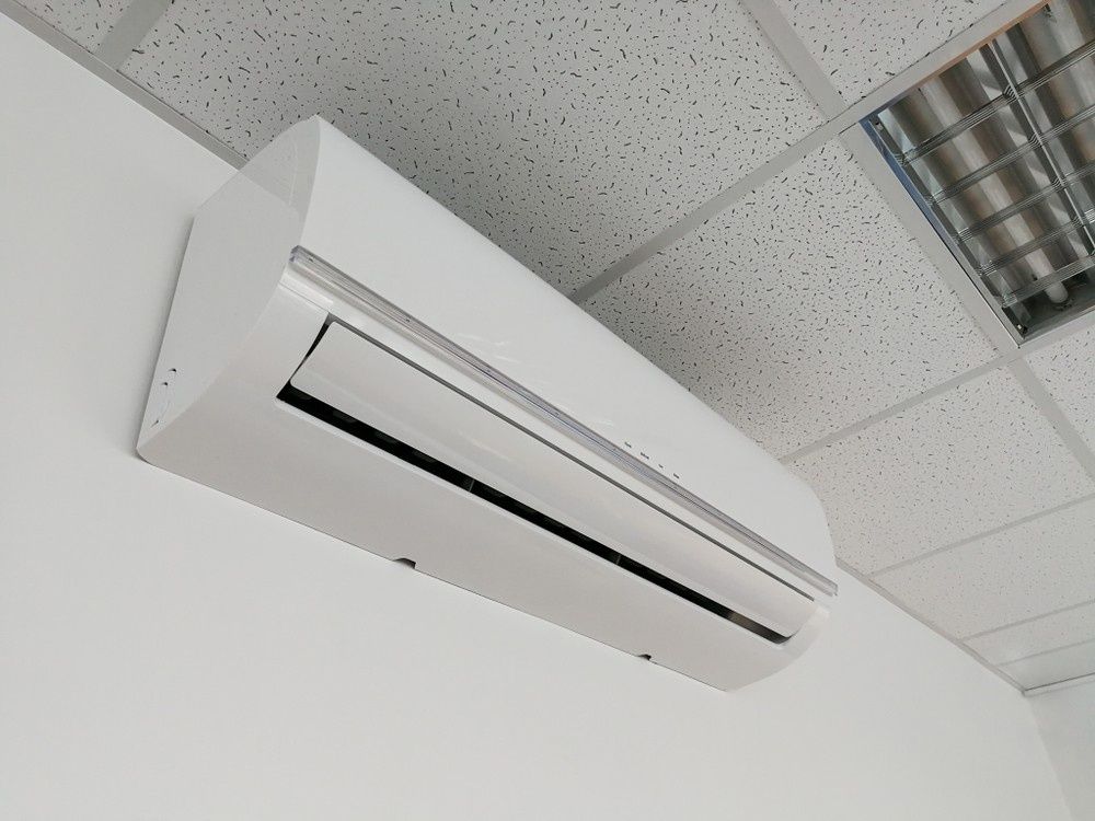 A White Air Conditioner Unit Mounted on A White Wall — Magneto HVAC in Cardwell, QLD