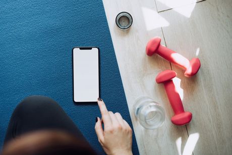 A person is pointing at a cell phone on a yoga mat.