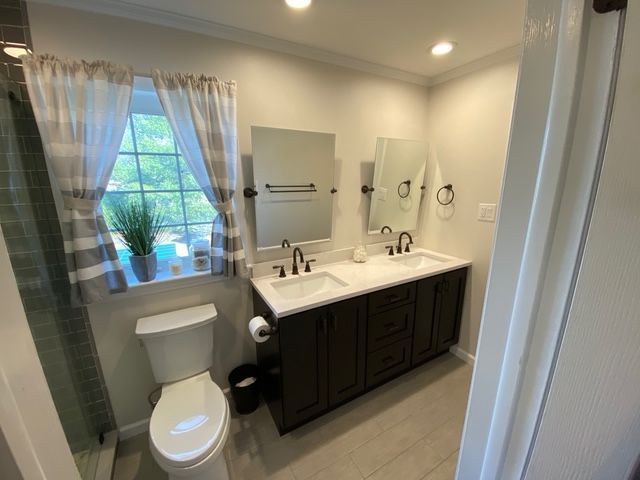 Bathroom with double sinks, dark cabinets, gray walls, and a window with curtains.