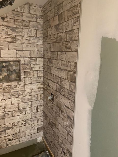Brick-patterned wallpaper on a wall; a frame hangs on the left.  The right side is painted a light color.