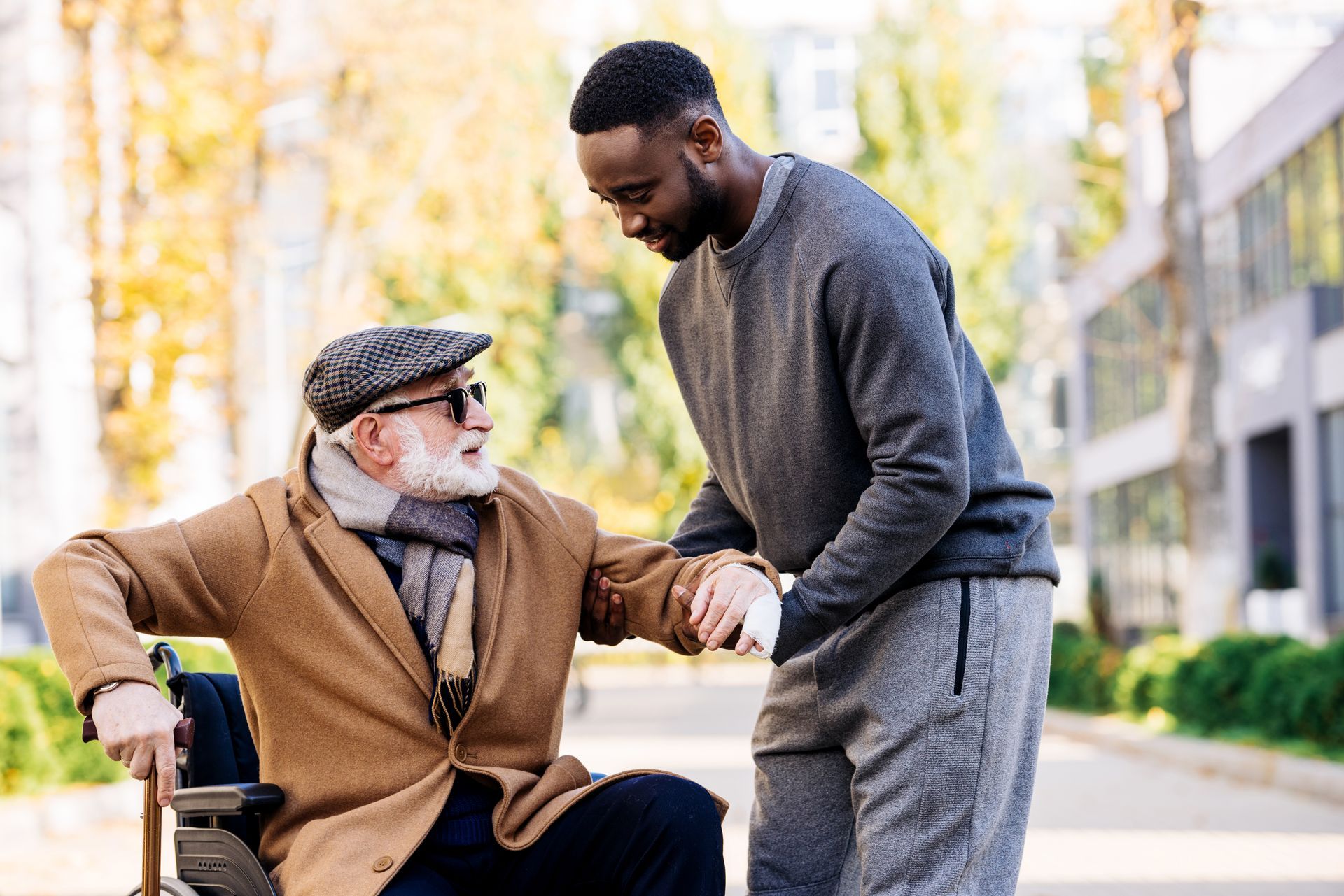 A man is helping an older man in a wheelchair.