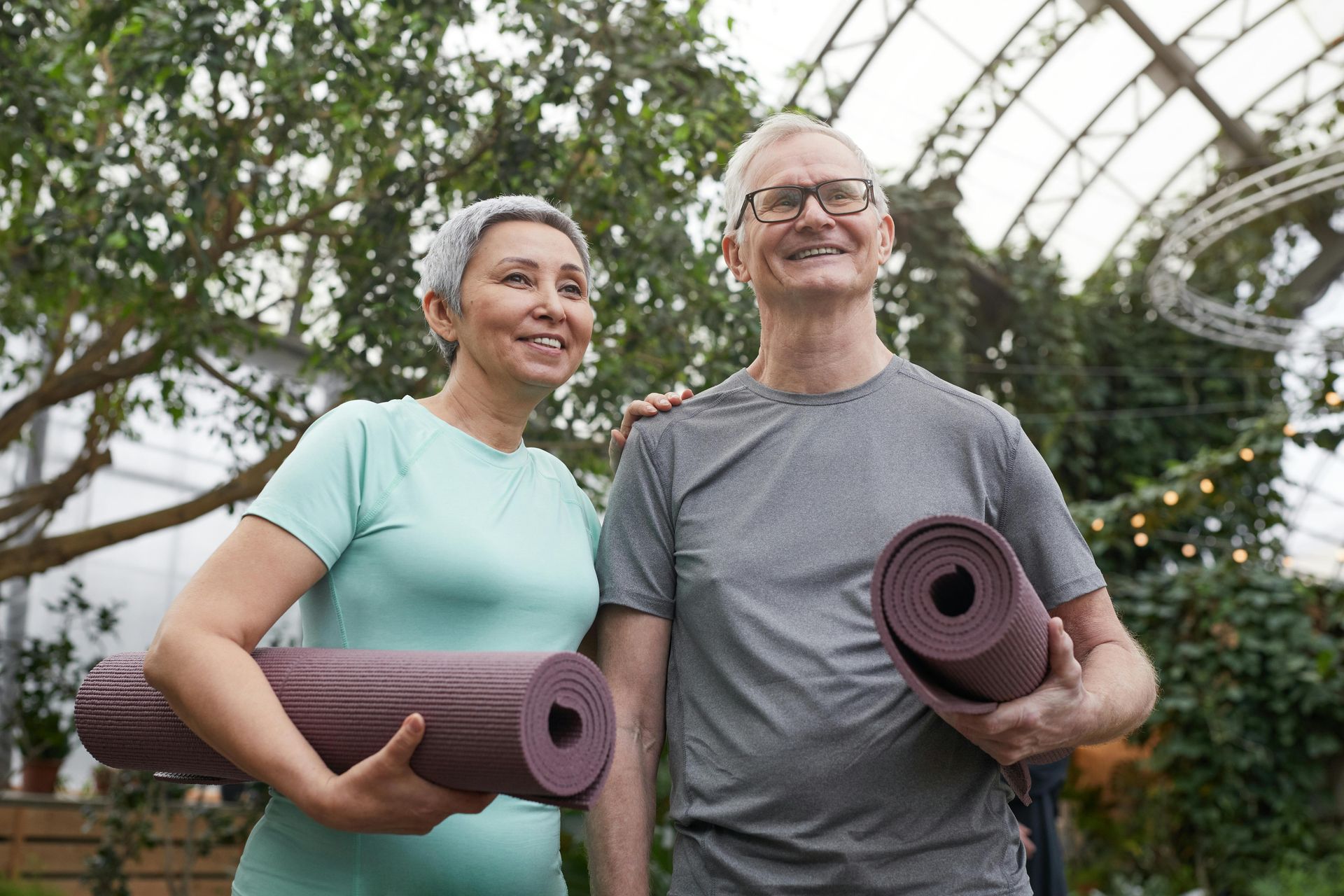 A man and a woman are standing next to each other holding yoga mats.