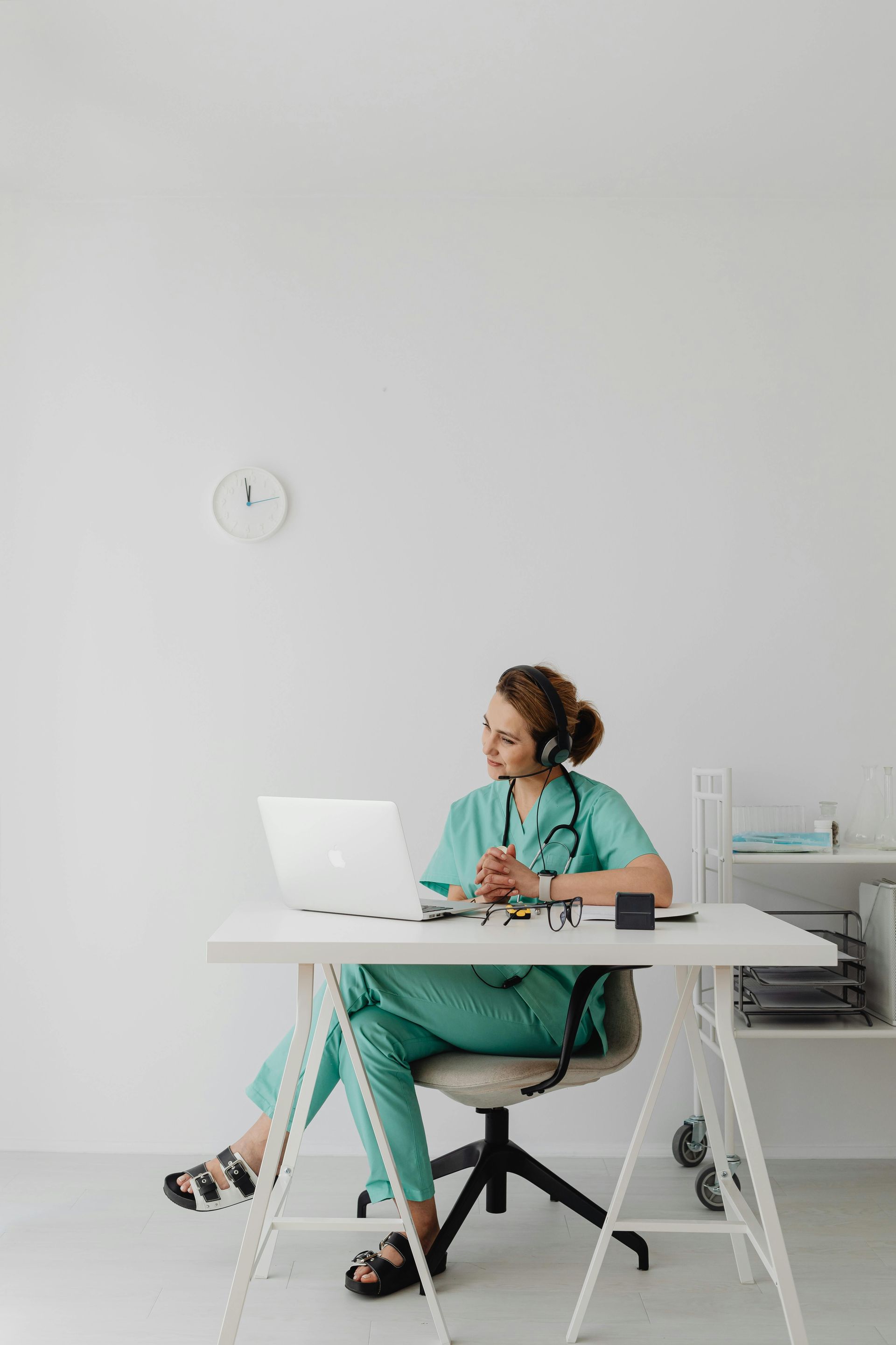 A nurse is sitting at a desk using a laptop computer.