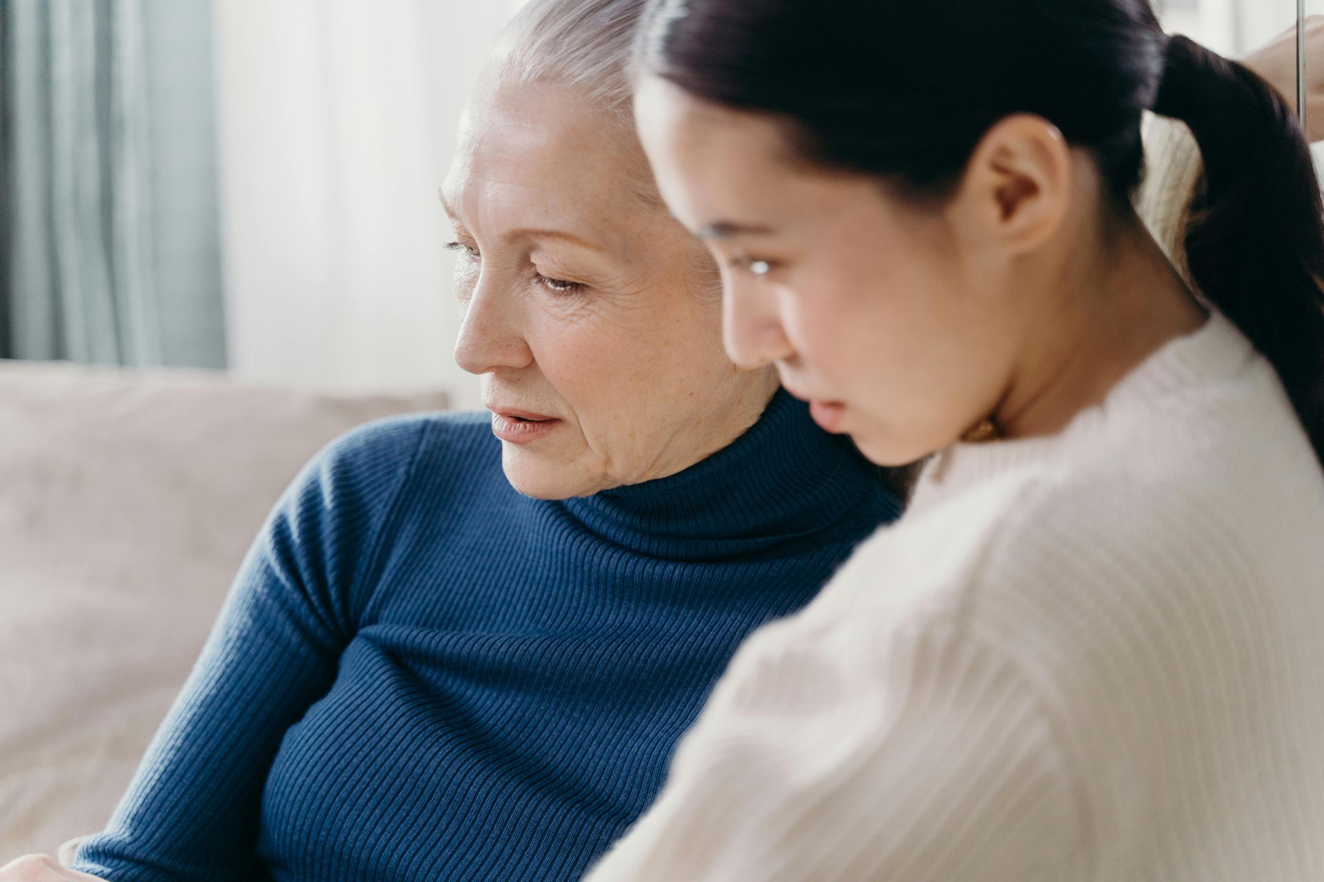 A young woman is sitting next to an older woman on a couch.