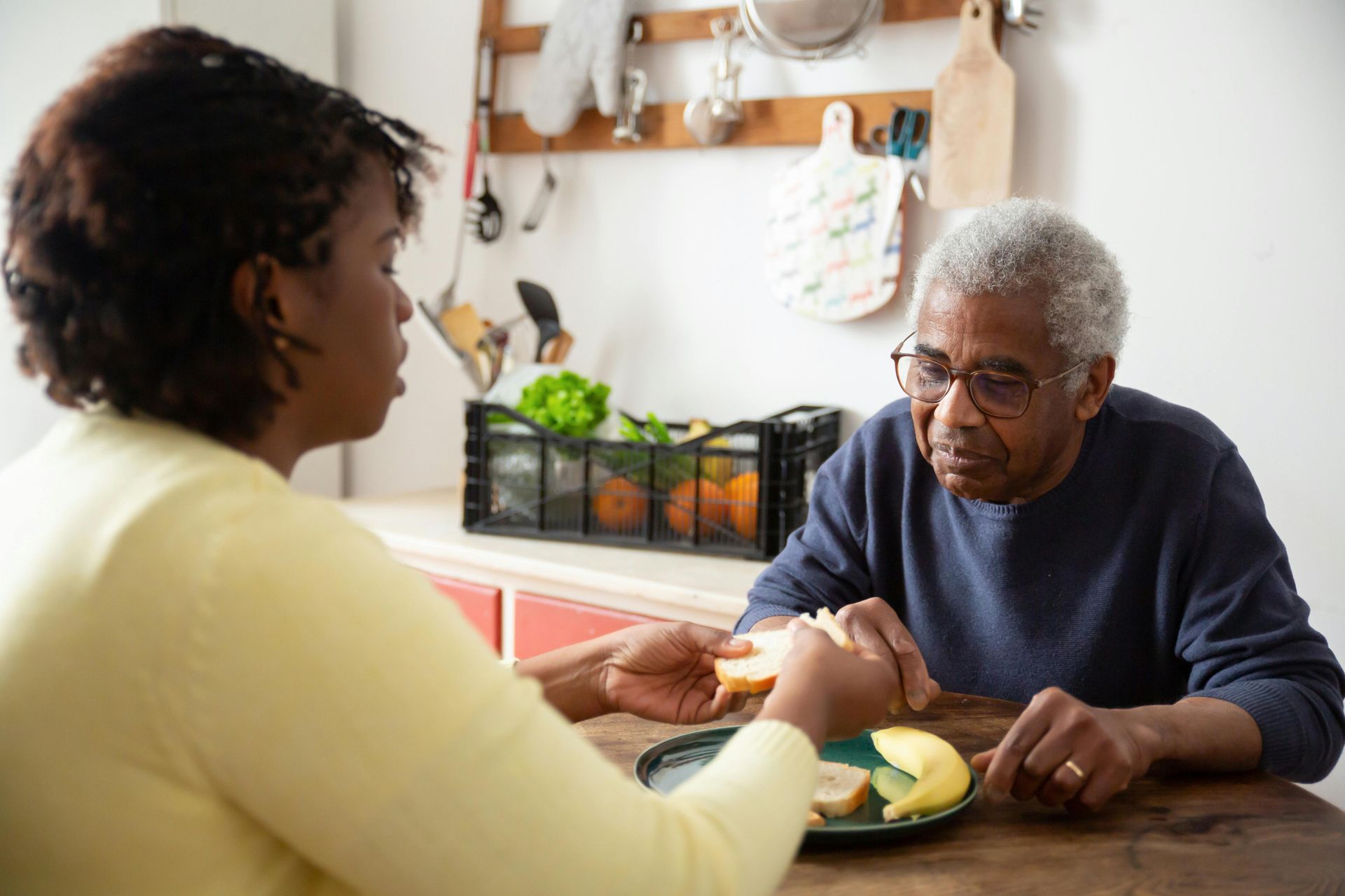 An elderly man and a woman are sitting at a table eating food.