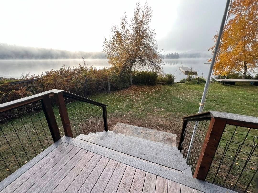 Wooden stairs lead down to a lake on a foggy autumn morning.