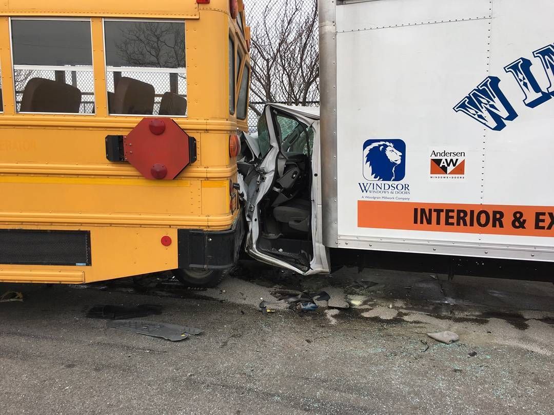 Yellow bus and white truck after a side-impact crash on a wet road, with visible damage and debris.