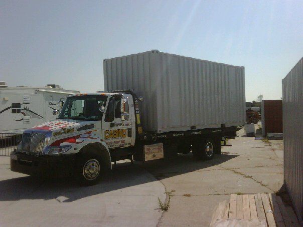 Box truck with a white cargo container parked in an industrial lot on a sunny day.
