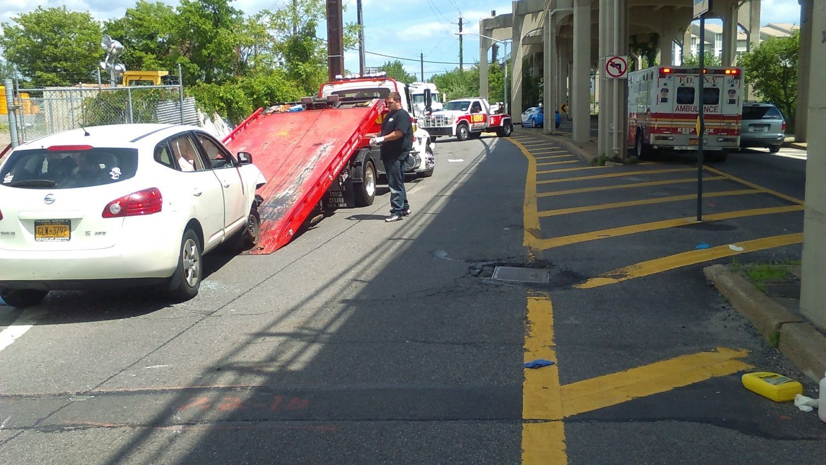 Car on tow truck being loaded on a street beside a train platform