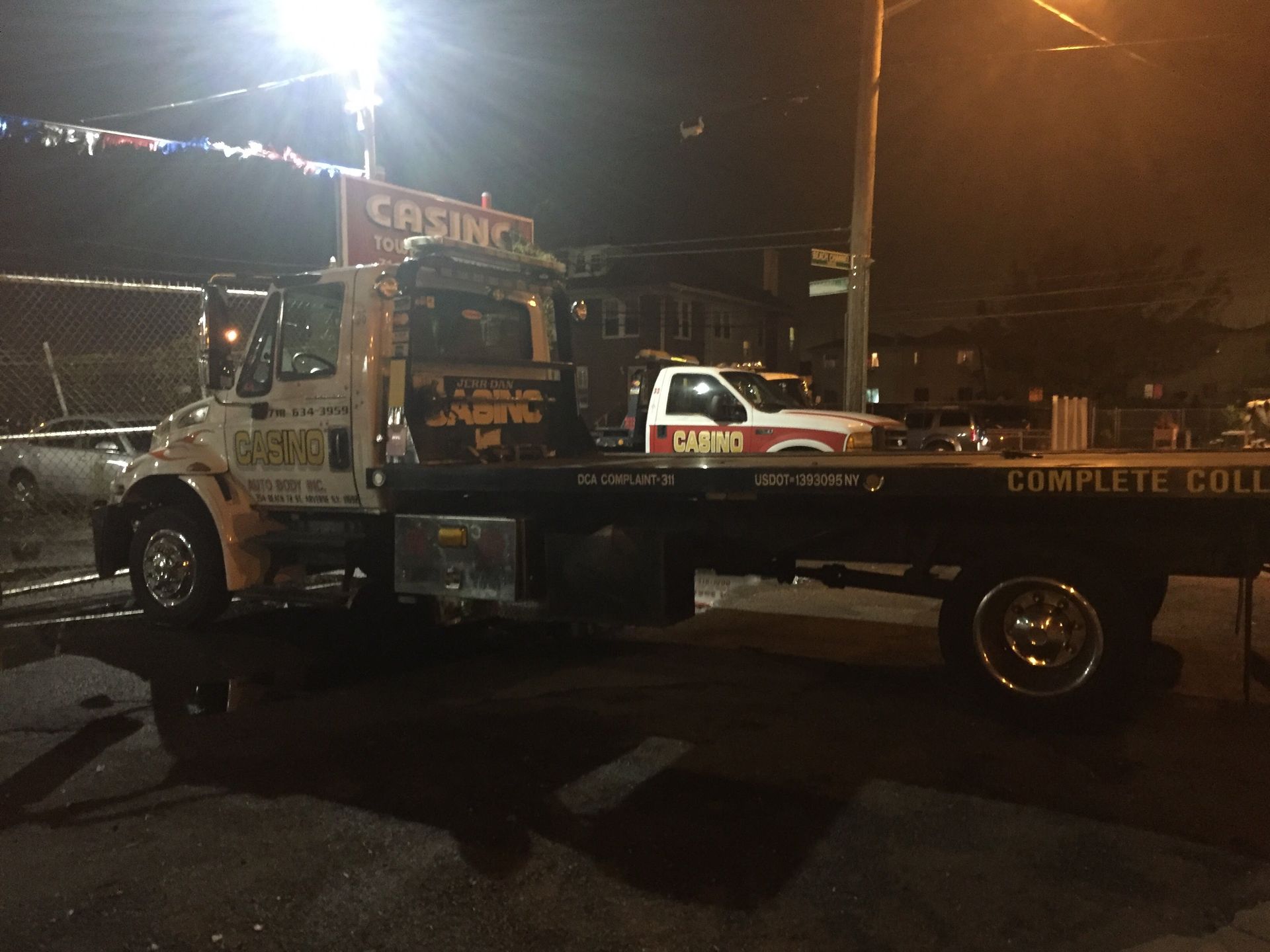 Tow truck at night with a pickup loaded on the flatbed in a parking lot