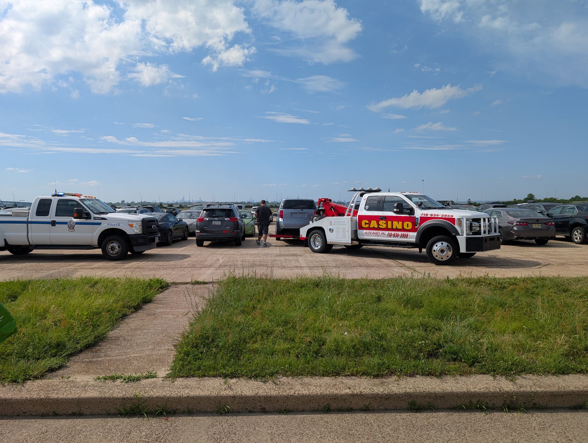 Parking lot with several pickup trucks, including a sheriff truck, under a blue sky