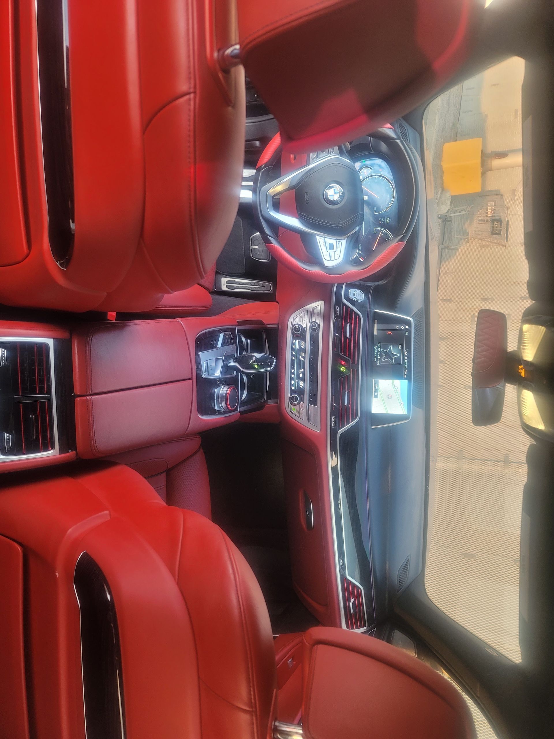 Red leather car interior with dashboard, steering wheel, and sunlit windshield view