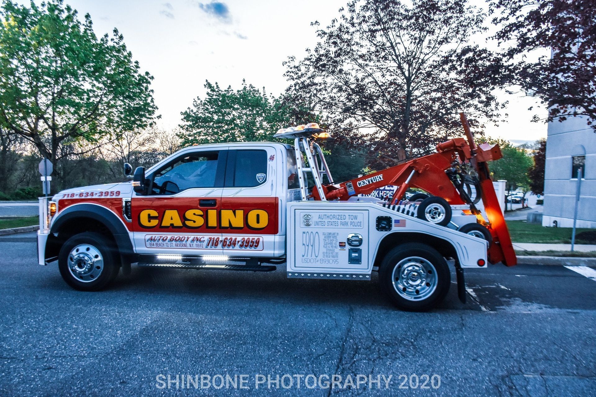 Red casino tow truck parked on a street with trees in the background.