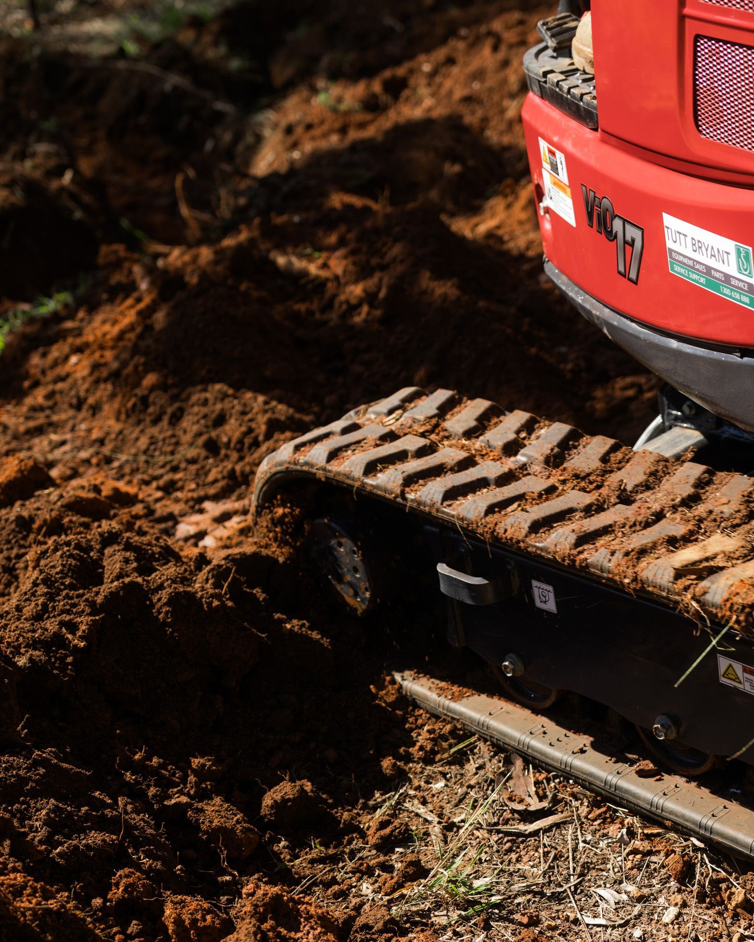 A small excavator bucket scoops up dirt in an outdoor setting.